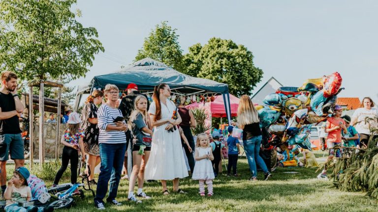 A lively outdoor gathering with families enjoying balloons and a sunny day.